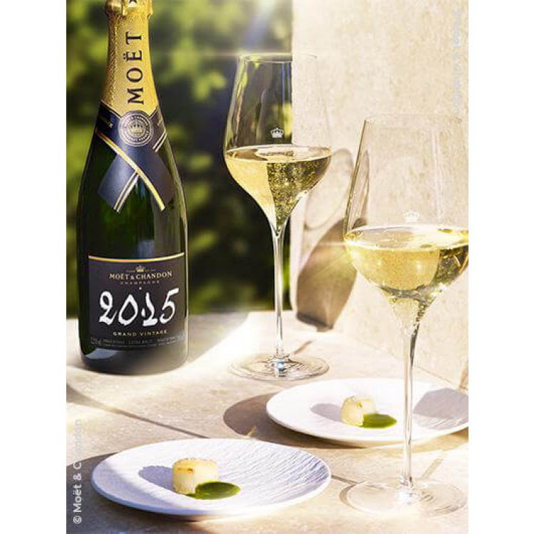 bouteille de moet et chandon grand vintage 2015 75cl sur une table avec du cavier et deux verres
